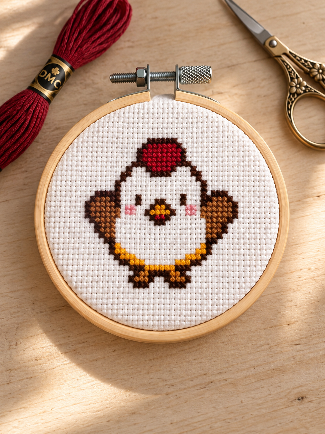 Mabel the Chicken cross-stitched on white fabric in a wooden hoop